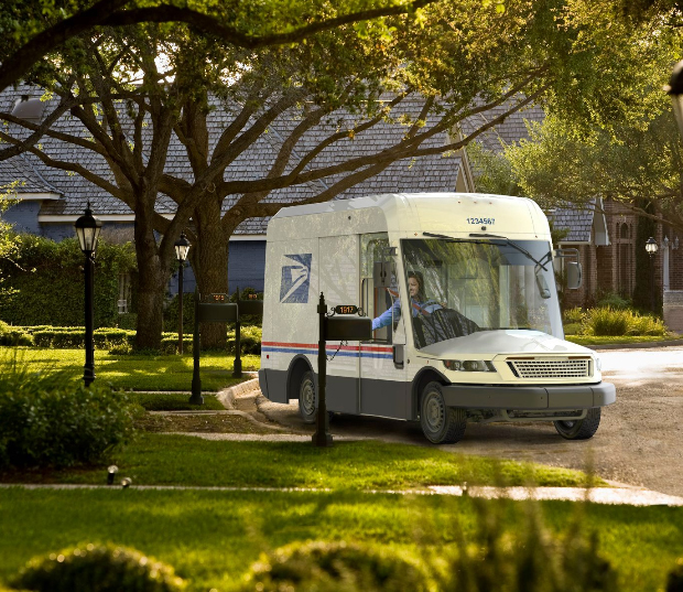 A futuristic looking electric postage truck pulls up to a mailbox.
