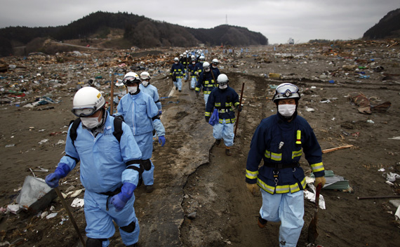Rescue workers make their way through an area devastated by a tsunami as they search for victims in Rikuzentakata March 21, 2011.