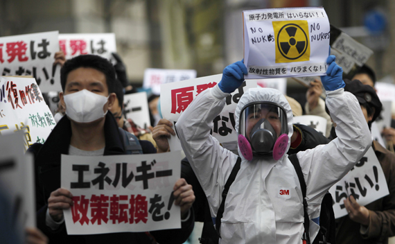 Protesters take part in an anti-nuclear rally in Tokyo March 27, 2011. The sign on the left reads,