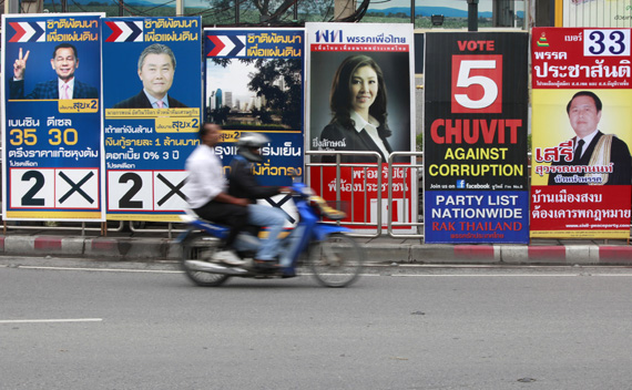 A motorcyclist rides past posters of candidates for the upcoming mayoral elections in Bangkok June 13, 2011.