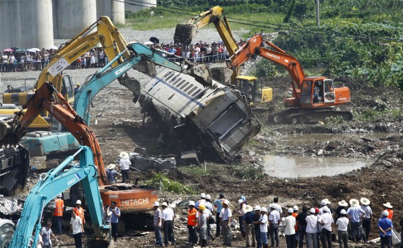 Workers and rescuers look on as excavators dig through the wreckage after a high speed train crashed into a stalled train in Wenzhou, Zhejiang province on July 24, 2011.