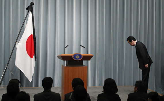 Japan’s Prime Minister Naoto Kan bows to the national flag as he arrives for a news conference at his official residence in Tokyo April 1, 2011.