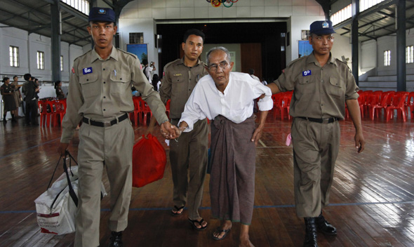 Police assist a newly released prisoner in the meeting hall of Insein Prison in Yangon.