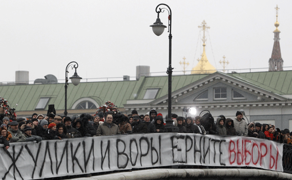 People attend a sanctioned rally on a bridge near Bolotnaya square to protest against violations at the parliamentary elections in Moscow December 10, 2011. Tens of thousands of protesters took to the streets of cities across Russia on Saturday to demand an end to Vladimir Putin’s rule and complain about alleged election fraud in the biggest show of defiance since he took power more than a decade ago. The banner reads