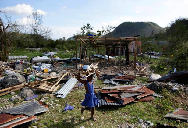 An adolescent girl carrying wood walks near debris after Hurricane Matthew passed, in Camp Perrin, Haiti, October 8, 2016. REUTERS/Andres Martinez Casares