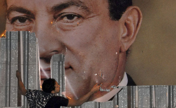 An anti-government protester defaces a picture of Egypt’s President Hosni Mubarak in Alexandria.