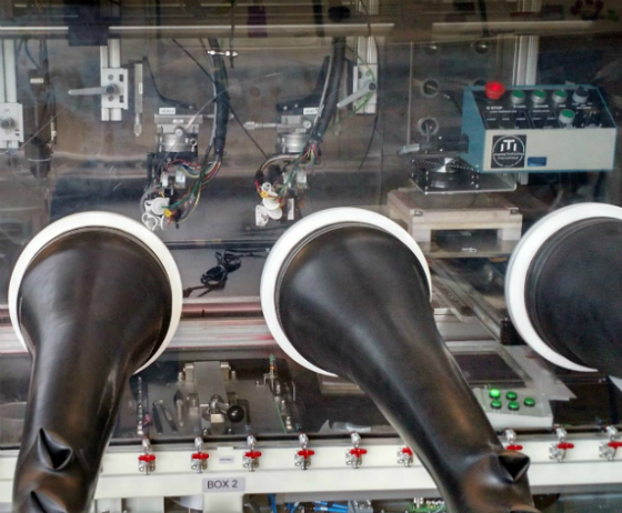 Prototype printer heads for inkjet printing perovskite solar coatings in a scalable manufacturing process. The process is contained inside a “glovebox,” into which researchers can reach, through the rubber arms, to interact with the process under a controlled atmosphere.