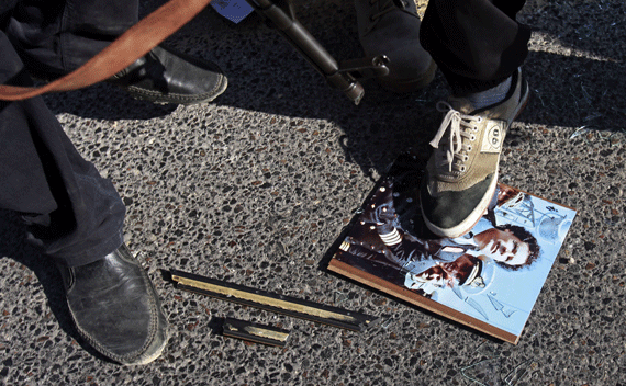 Libyan rebel fighters step on a picture of Muammar Gaddafi at a checkpoint in Tripoli’s Qarqarsh district August 22, 2011