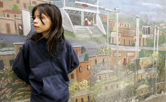 A girl stands in front of a mural as she waits for Spain’s King Juan Carlos and Queen Sofia for the inauguration of a public library in a suburb of Medellin (Jose Gomez/Courtesy Reuters).