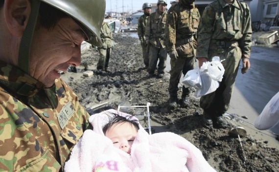 A Japan Self-Defense Forces officer smiles as he holds a four-month-old baby girl who was rescued along with her family members from their home in Ishimaki City, Miyagi Prefecture in northern Japan, after an earthquake and tsunami struck the area on March 14, 2011.