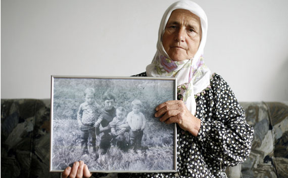 Munira Salihovic poses with picture of her three sons and husband, who were killed during the Srebrenica massacre.