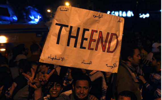 Anti-government protesters carry a placard and celebrate Mubarak’s departure in Tahrir square on February 11, 2011.