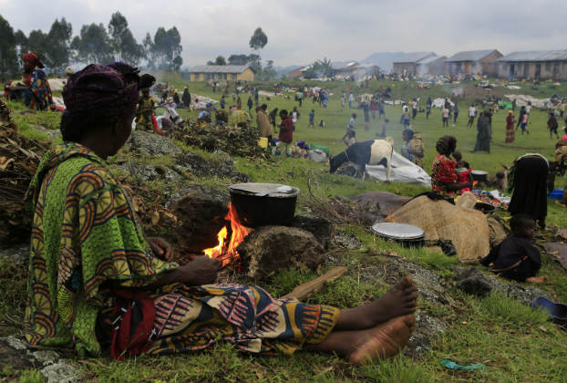 A woman displaced by fighting between the Congolese army and M23 rebels in eastern Democratic Republic of Congo prepares dinner in a field with other displaced families. (James Akena/Reuters)