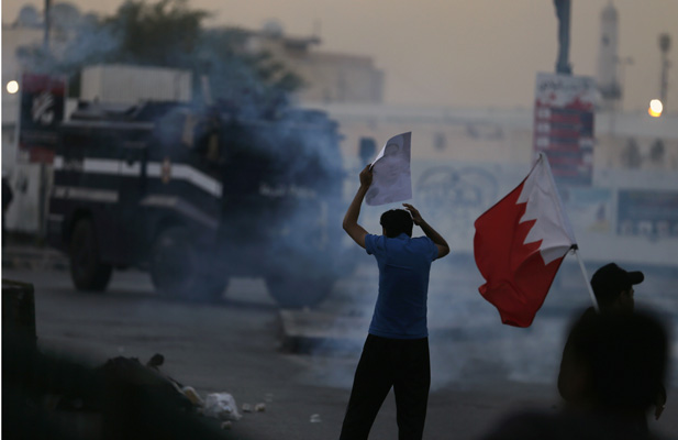 A Bahraini demonstrator confronts riot police following the detention of Shia opposition leader Sheikh Ali Salman