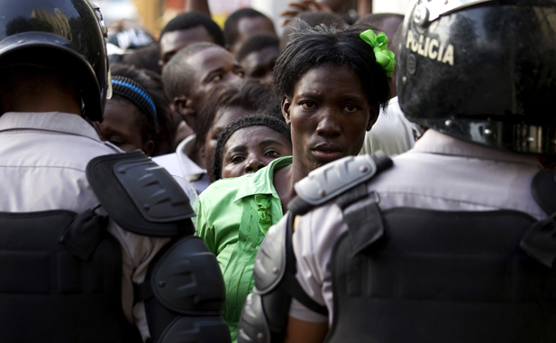 Haitians face police while waiting outside the Ministry of Interior and Police to register in Santo Domingo
