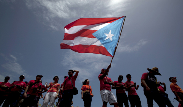 A man waves a Puerto Rican flag during a protest in a May 2015 protest in San Juan. University students and employees took to the streets to oppose proposed cuts to public university budgets.
