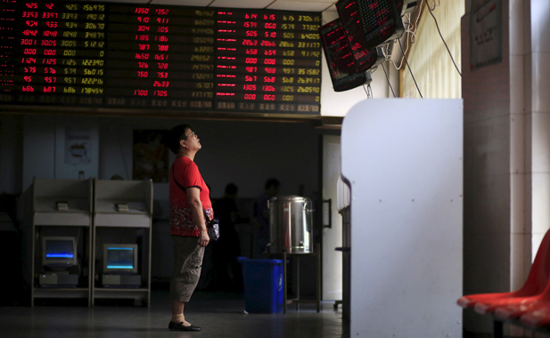 An investor looks at electronic stock information board in Shanghai, China