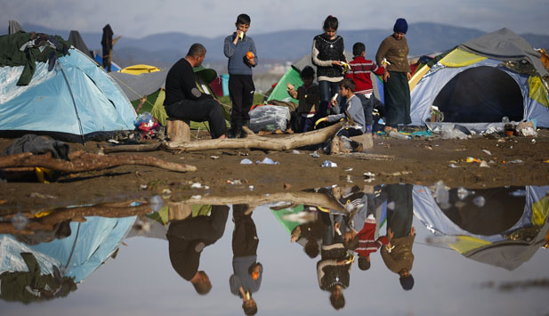 Migrants rest near their tents at a makeshift camp on the Greek-Macedonian border, near the village of Idomeni, Greece