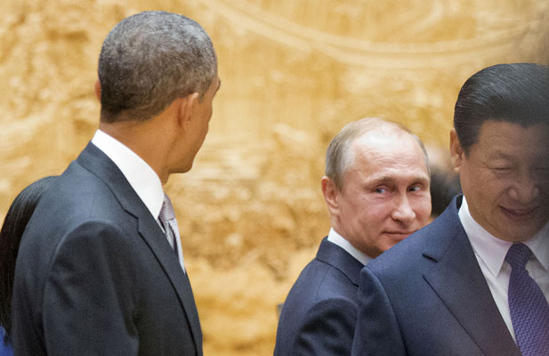 Russian President Vladimir Putin looks back at U.S. President Barack Obama as they arrive with Chinese President Xi Jinping at an APEC Summit plenary session in Beijing in 2014. (Pablo Martinez Monsivais/Reuters)