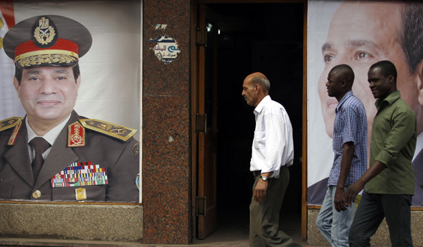 People walk past posters of presidential candidate and former army chief Abdel Fattah al-Sisi at one of his campaign headquarters in central Cairo April 16, 2014.