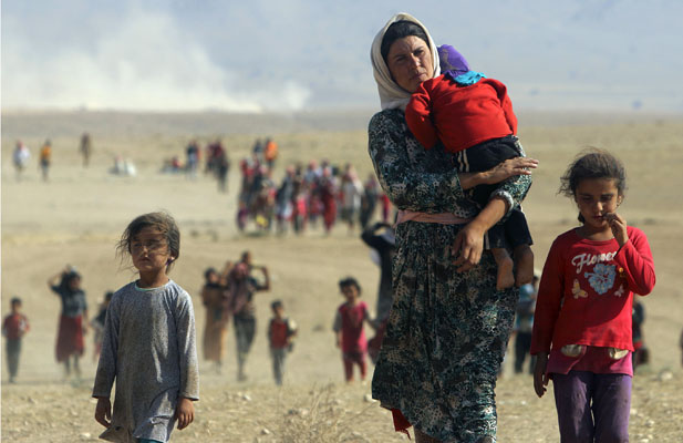 Displaced people from the minority Yazidi sect, fleeing violence from forces loyal to the Islamic State in Sinjar town, walk towards the Syrian border on the outskirts of Sinjar mountain
