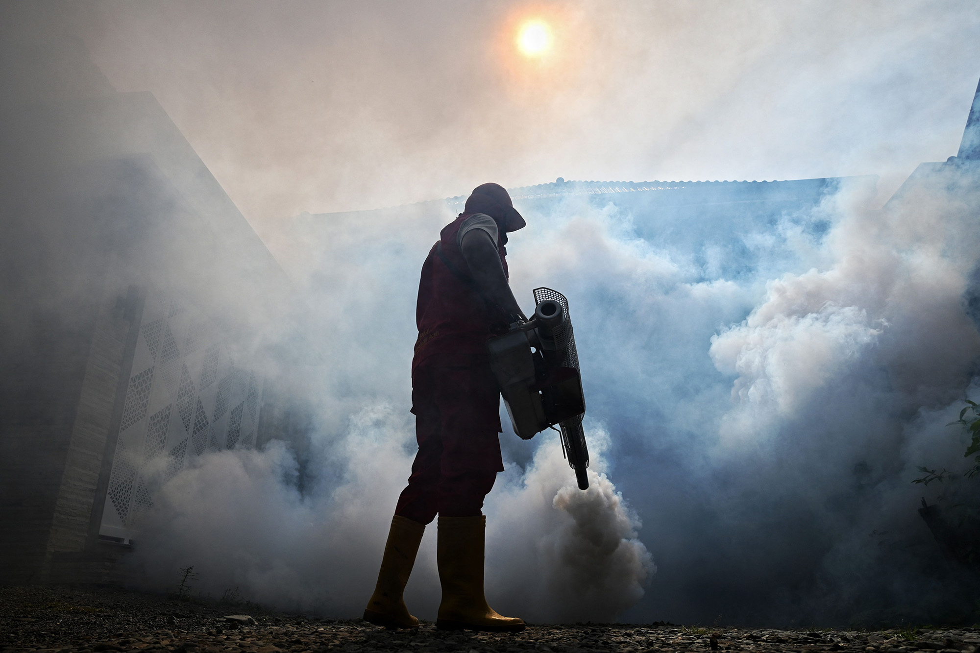 Silhouette of a worker spraying insecticide to kill mosquitoes.