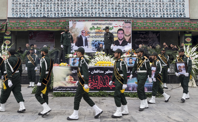 Iranian soldiers walk past coffins of two members of the Iranian Revolutionary Guards who were killed in Syria.