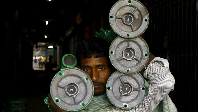 A laborer carries iron hand pumps through an alley at a wholesale market in Kolkata.