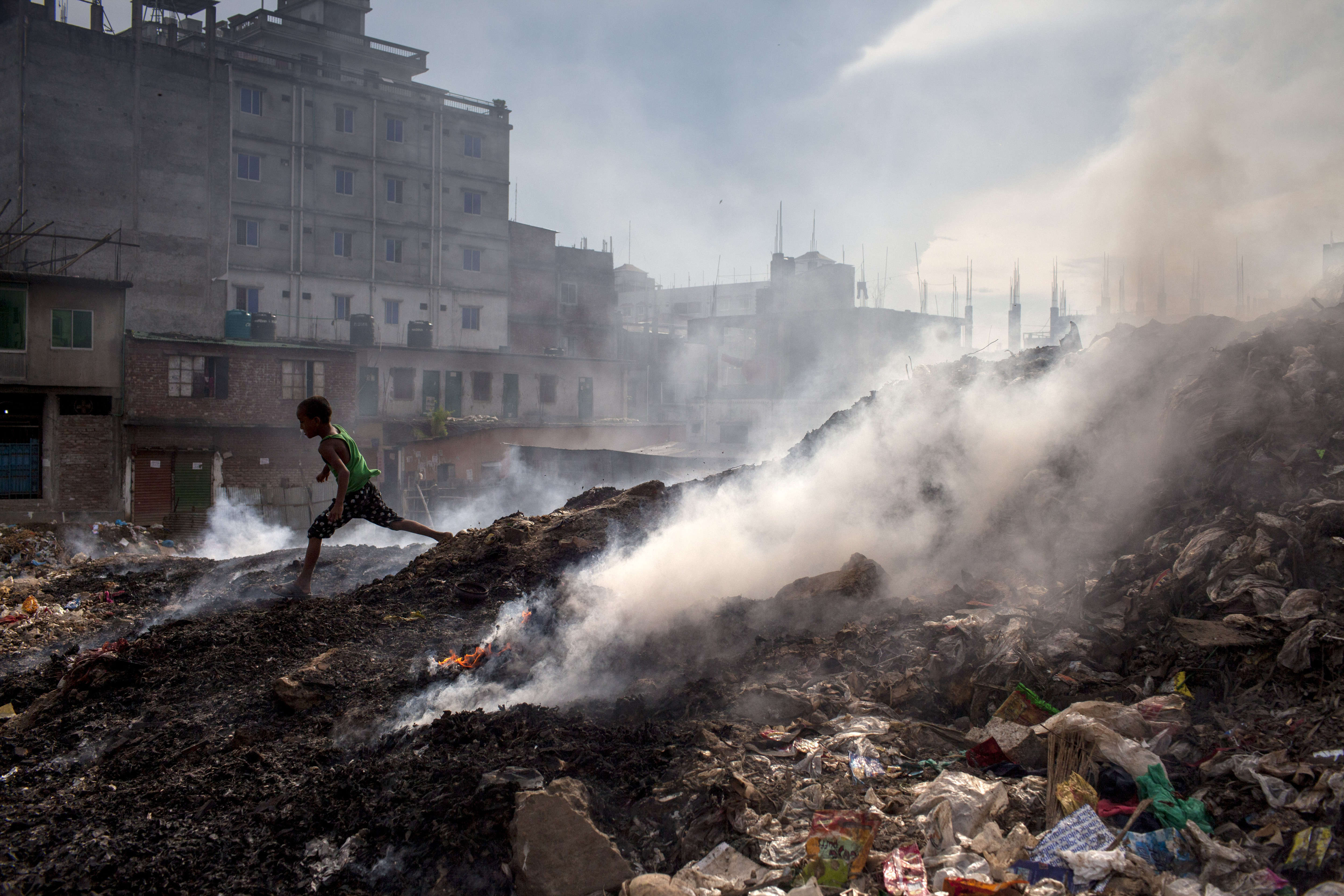 A child runs beside the waste-burning area of a dump in Dhaka, Bangladesh. 