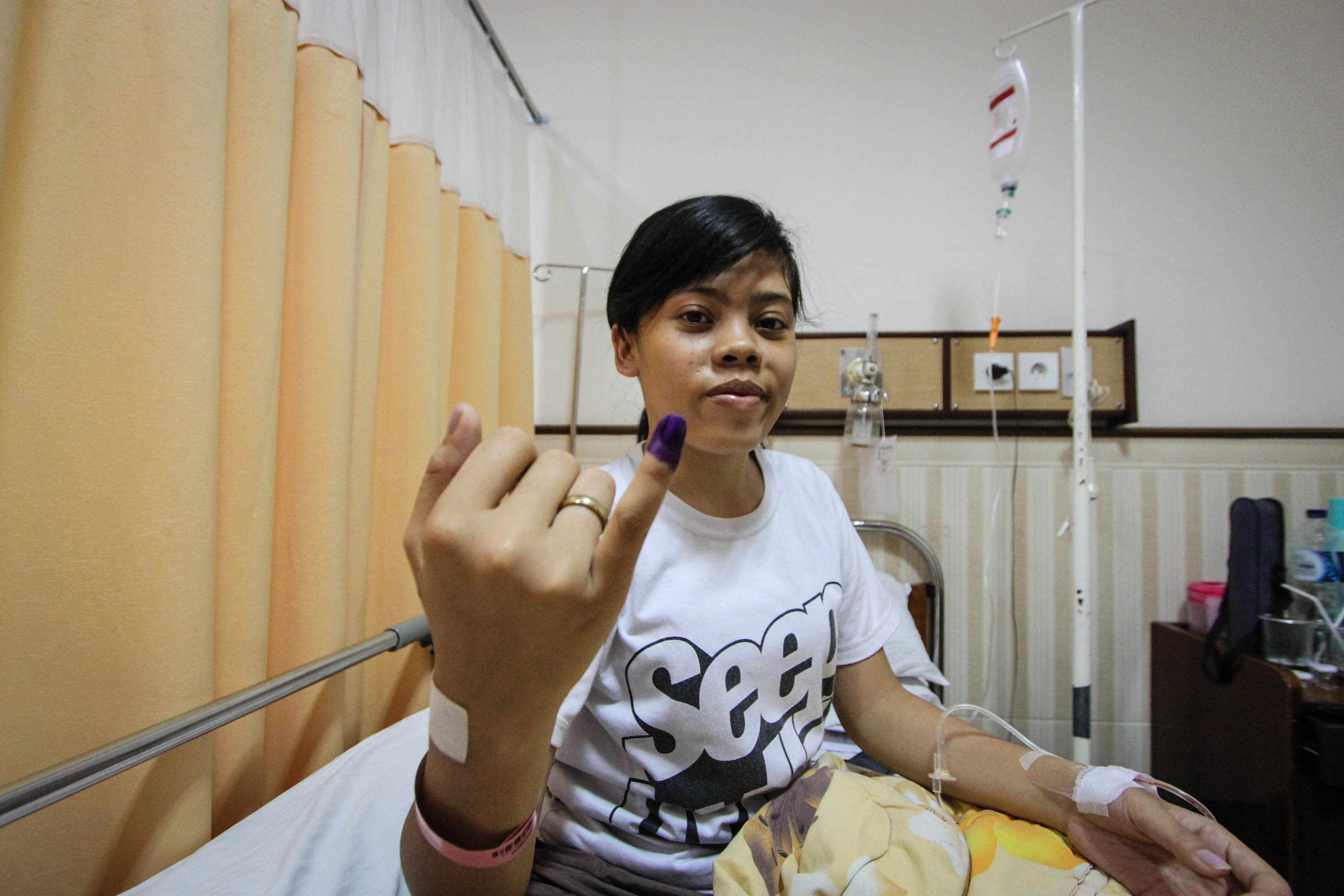 A woman shows her ink-stained finger after casting a ballot for the Indonesian presidential election at a hospital in Semarang, Indonesia.