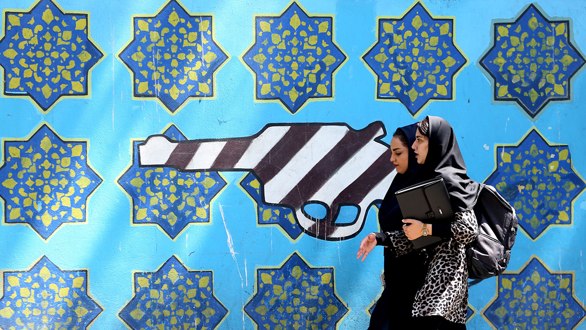 Women walk past a mural along the wall of the former U.S. embassy in Tehran.