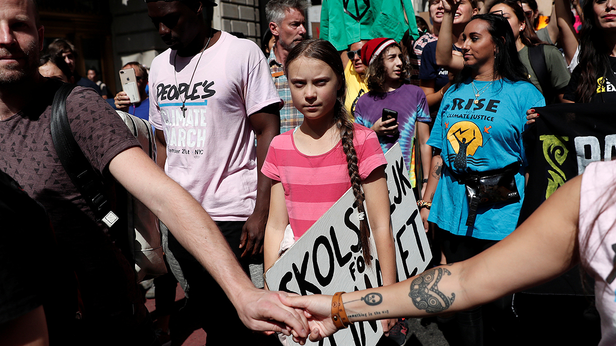 Greta Thunberg holds a sign amid a crowd of people during a climate protest.