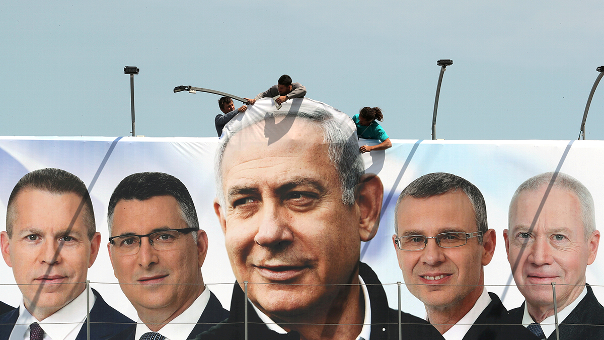 People hang a Likud Party campaign banner showing Netanyahu and party candidates in Jerusalem.