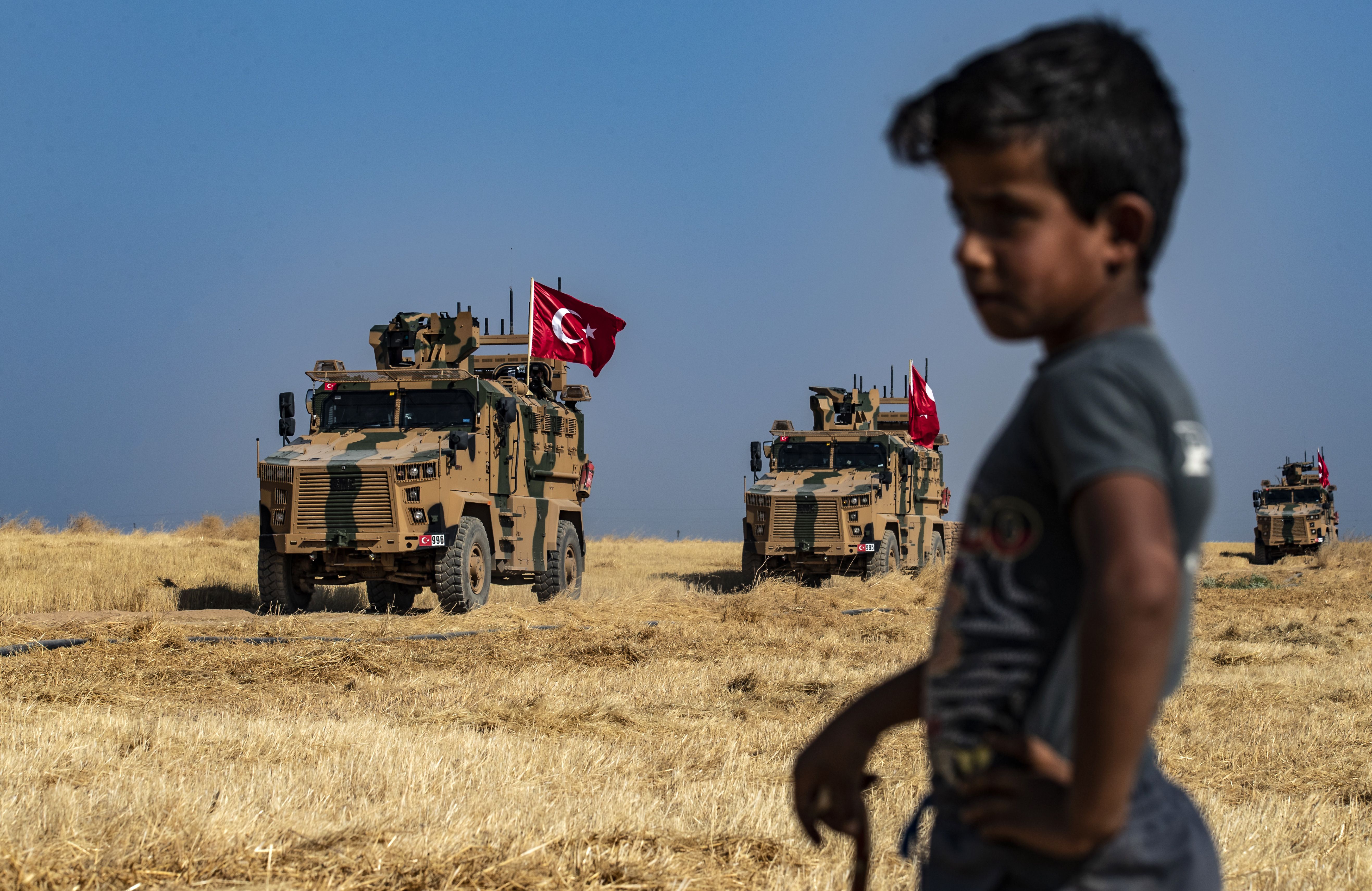 Turkish military vehicles, part of a U.S. military convoy, take part in a joint patrol in the Syrian village of al-Hashisha.