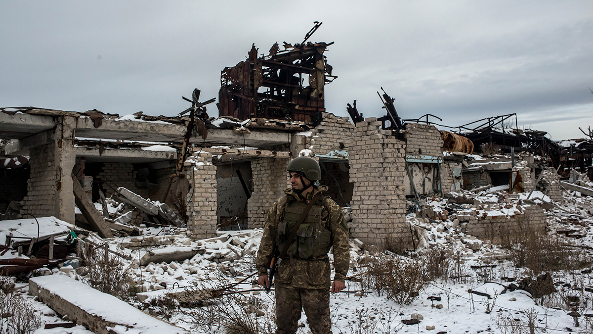 A Ukrainian Army soldier stands in front of destroyed buildings on the front line.