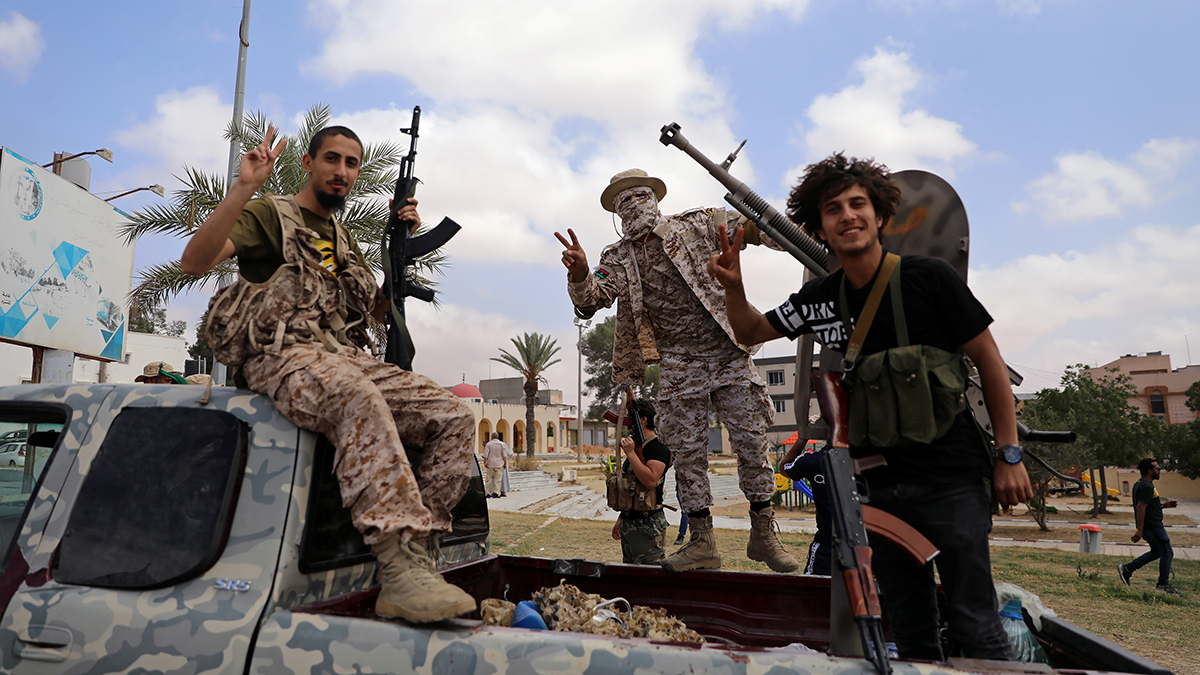 Three fighters loyal to Libya's UN-backed government pose holding guns on the back of a truck in the city of Tarhuna.