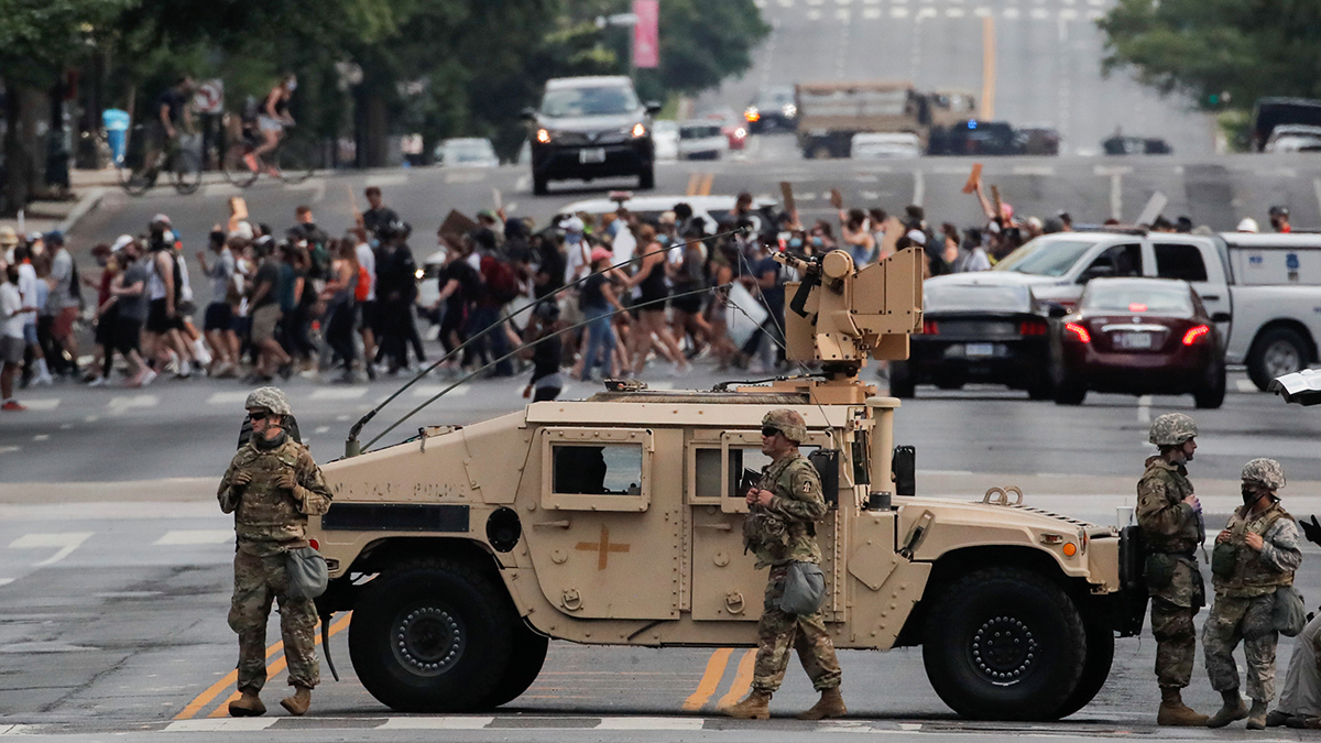 A military vehicle passes behind law enforcement personnel as protesters rally against the death of George Floyd, near the White House in Washington, DC, June 3, 2020. 