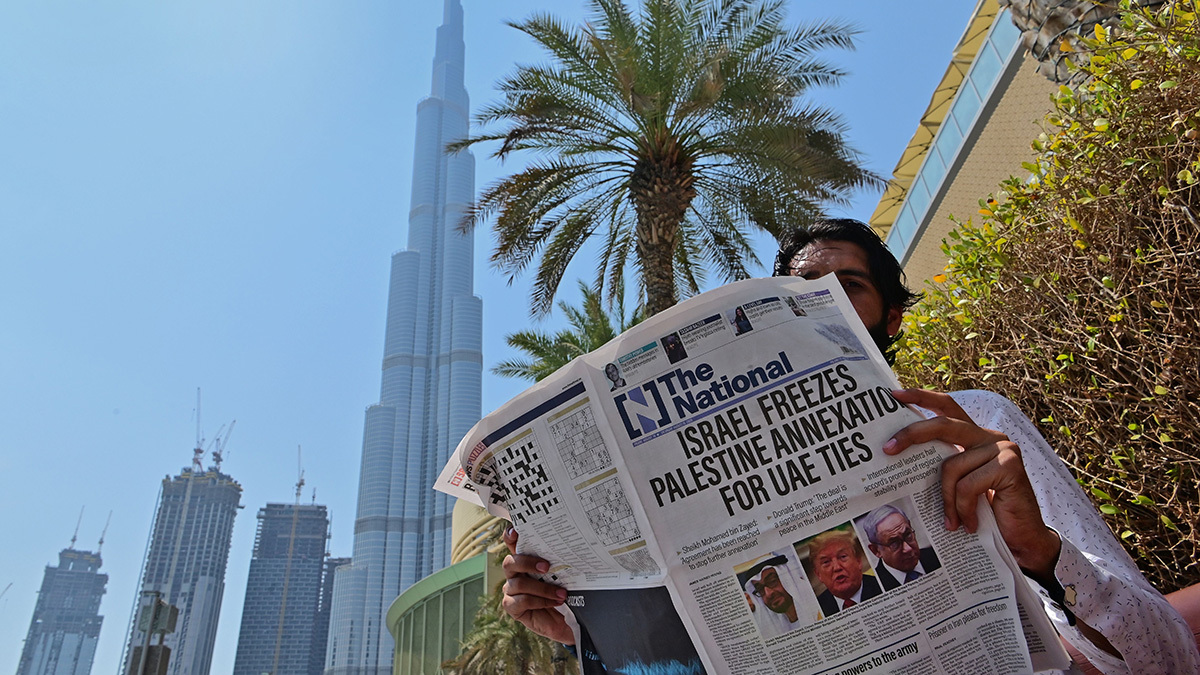 A man near the Burj Khalifa in Dubai reads a newspaper with the headline