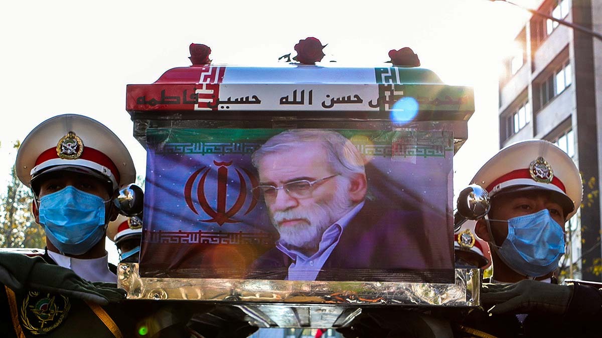 Iranian soldiers carry a coffin that has nuclear scientist Mohsen Fakhrizadeh's photo on one end and three roses on top