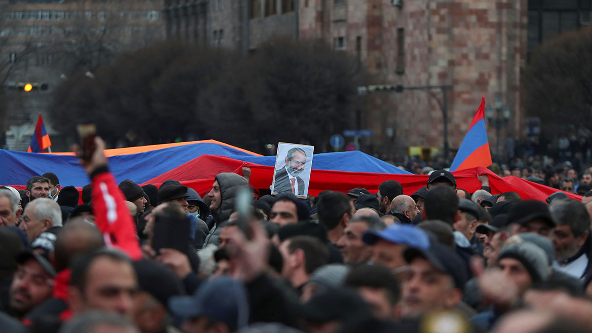  Protesters hold Prime Minister Nikol Pashinyan's picture in front of a massive Armenian flag at a rally in Yerevan.