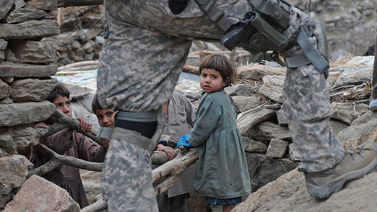 A U.S. soldier walks past playing children in the mountains of Afghanistan.