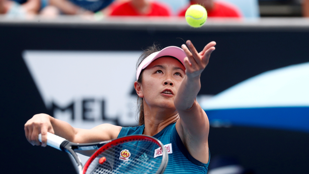 Chinese tennis player Peng Shuai tosses a tennis ball in the air.