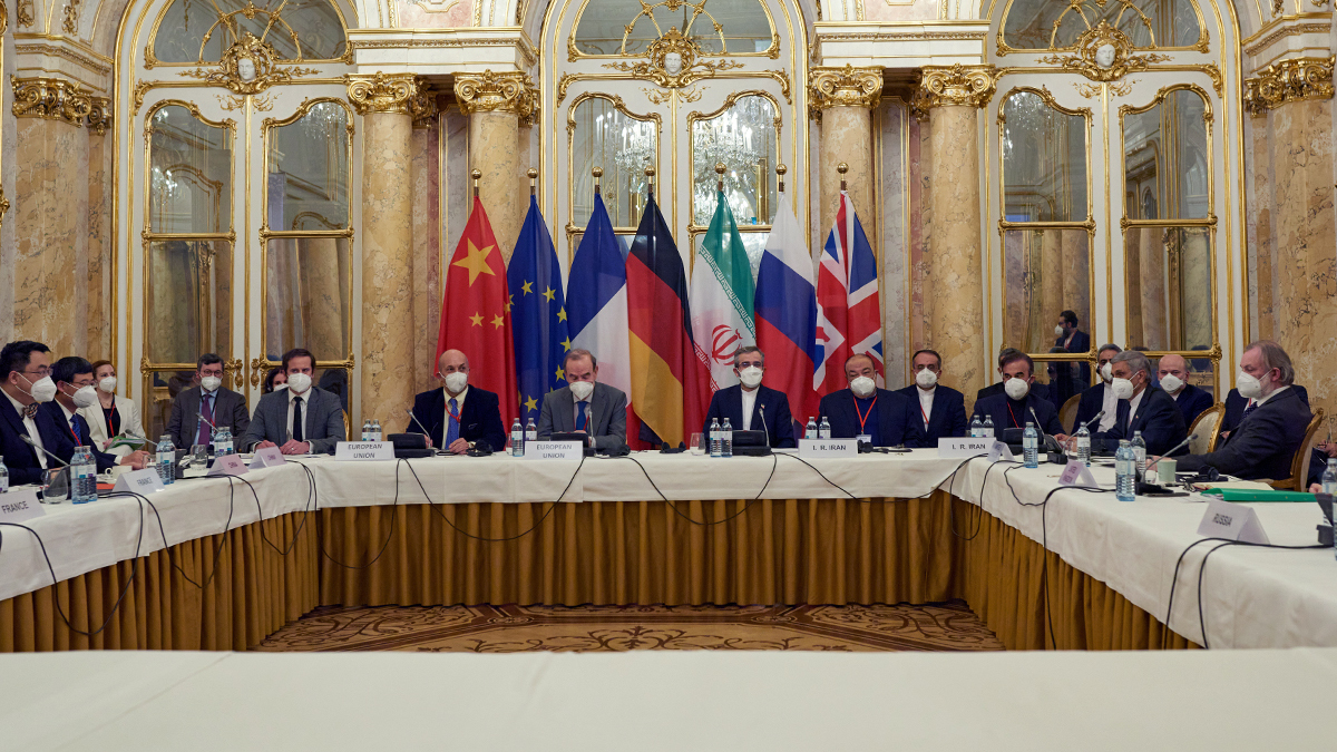 Negotiators sit in a square with the Chinese, EU, French, German, Iranian, Russian, and UK flags seen behind them.