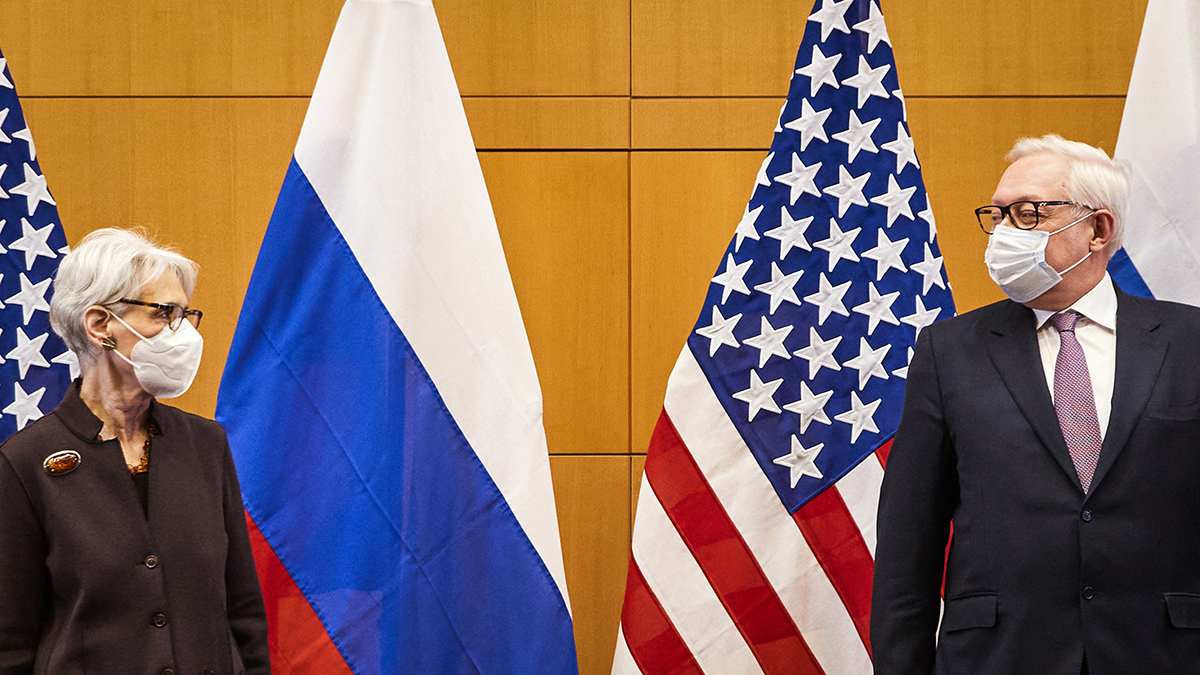 Wendy Sherman stands next to Sergei Ryabkov in front of U.S. and Russian flags.