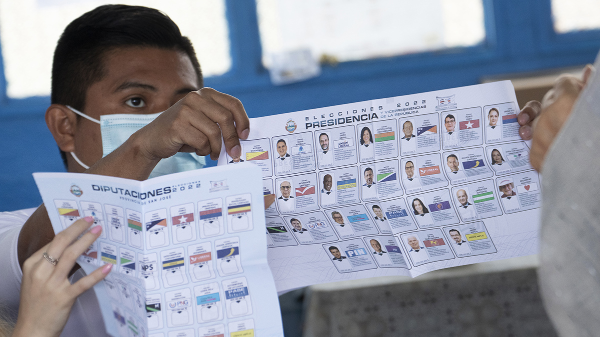 An election worker shows the presidential ballot to voters in San Jose, Costa Rica. 