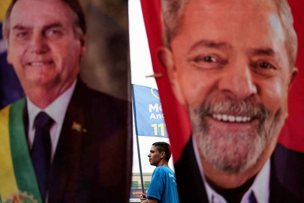 A man walks by campaign flags for President Jair Bolsonaro and former President Luiz Inácio Lula da Silva in Brasília, Brazil.