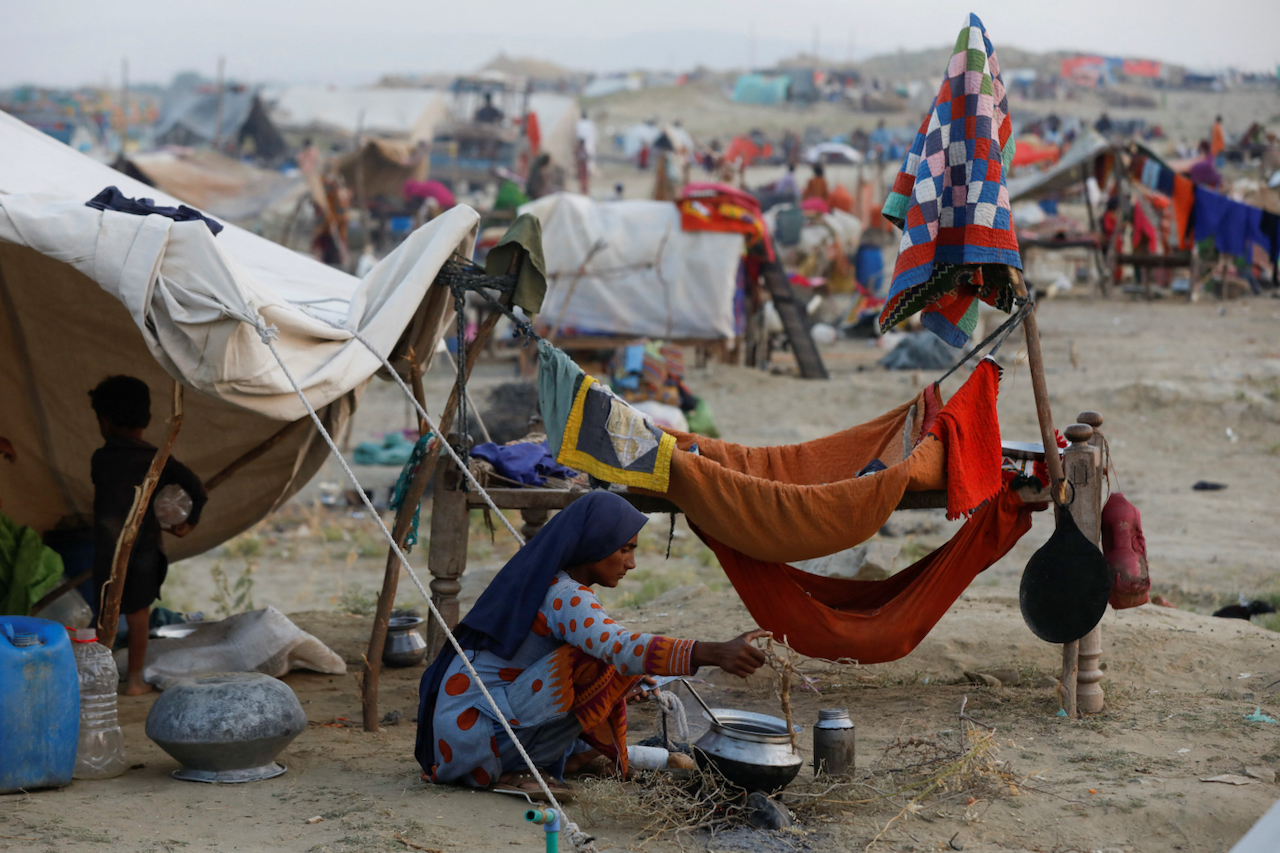 A woman cooks for her children in a displacement camp after widespread flooding in Pakistan.