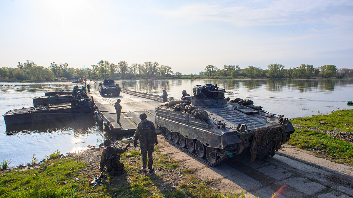 Marder infantry fighting vehicles roll across a floating bridge in Saxony, Germany.