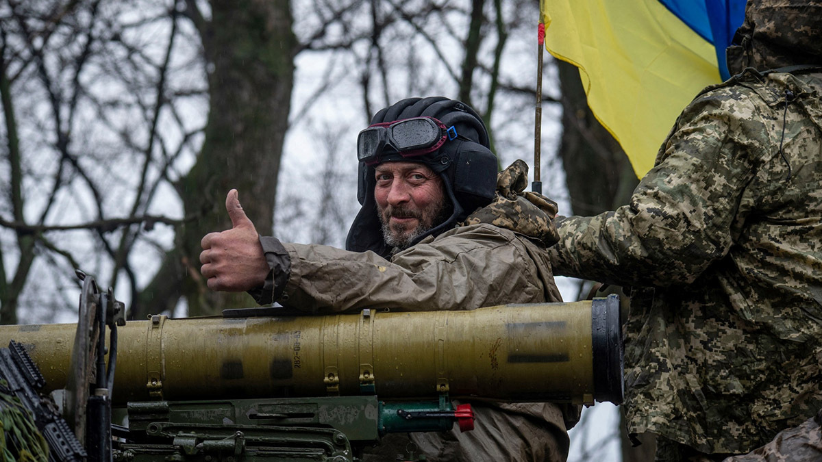 A member of the Ukrainian military rides on top of an armored fighting vehicle.