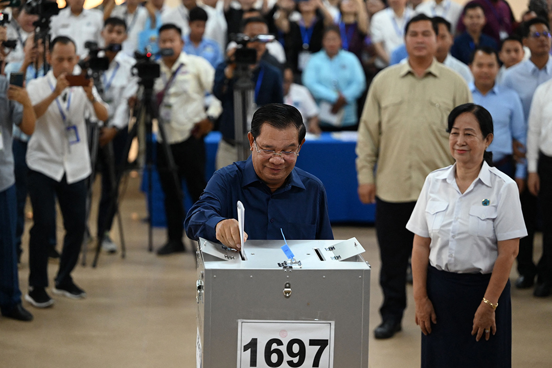 Onlookers watch as Cambodian President Hun Sen places a ballot in a ballot box